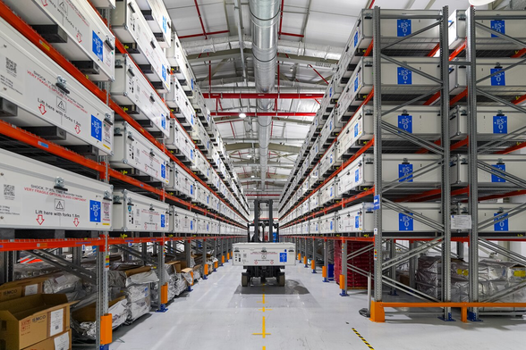A warehouse with metal structures holding white boxes with a blue ESO logo.