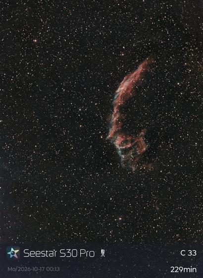 A colour photo of a portion of the night sky with thousands of visible stars. To the right of centre is a lacy filament of gases in a roughly crescent shape. The wisps are mostly red with some green and blue. There's a caption at the bottom: "Seestar S30 Pro - C 33 - Mo/2026-10-17 00:13 - 229min". This refers to the device used to capture the image, the name of the structure, my credits with time of capture, and the length of exposure.