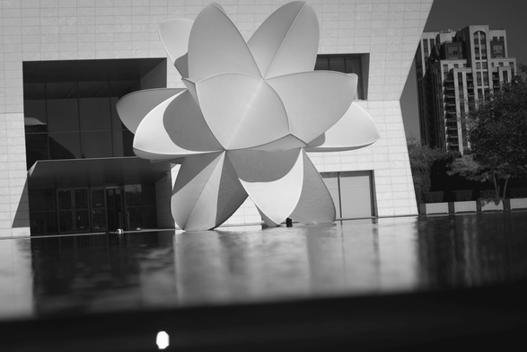 Black & white photograph of a large geometric shape sitting on a reflected in a large pool of water.