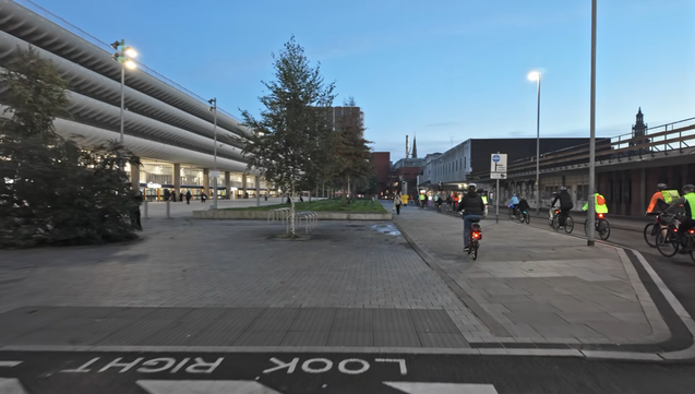 the iconic preston bus station in early evening, with dark blue hour sky and a whole bunch of cyclists on the road in front of it
