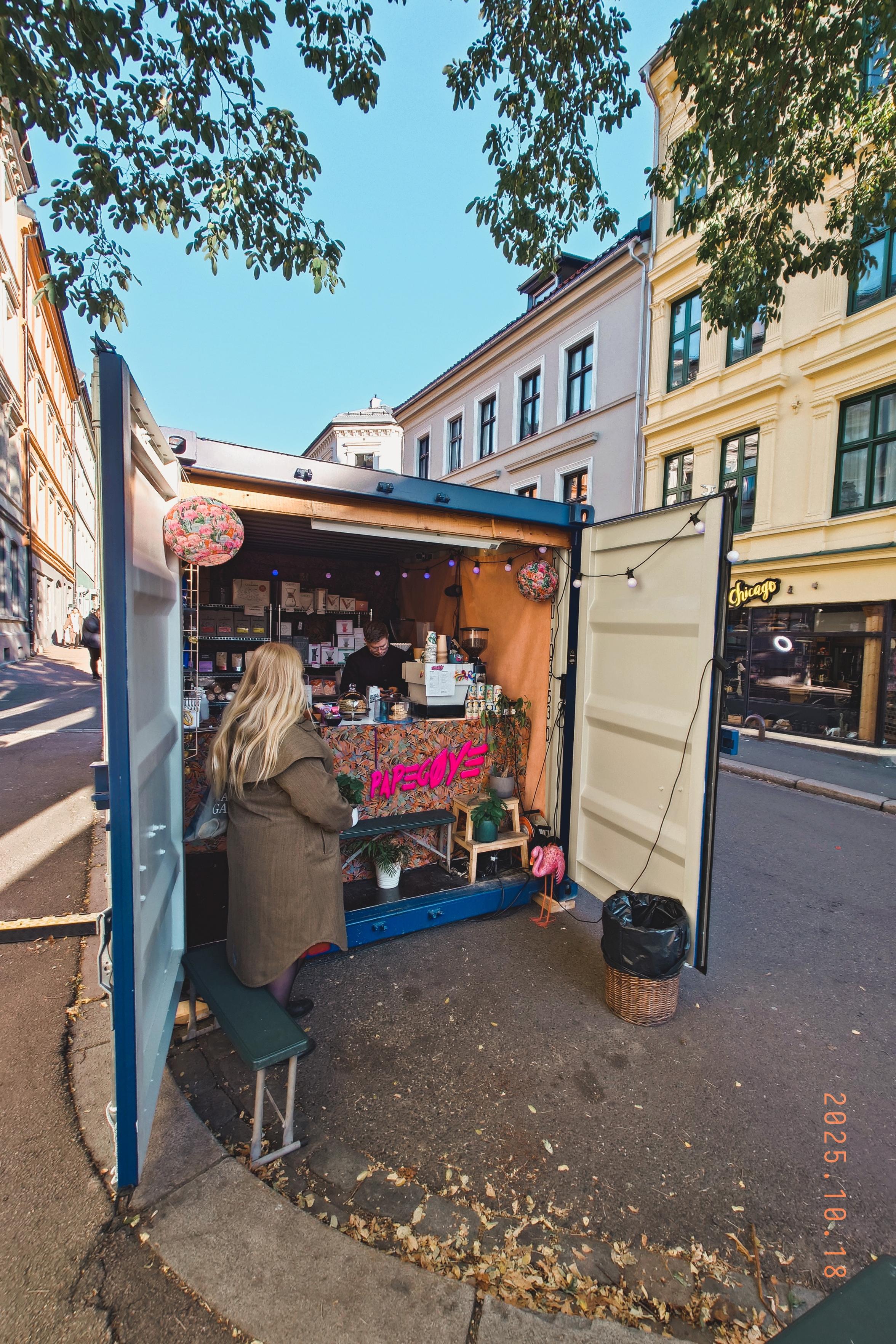 A photo of a shipping container at the side of a street with the doors open, revealing a temporary home for Papegøye, one of Oslo's cutest neighborhood coffee shops.