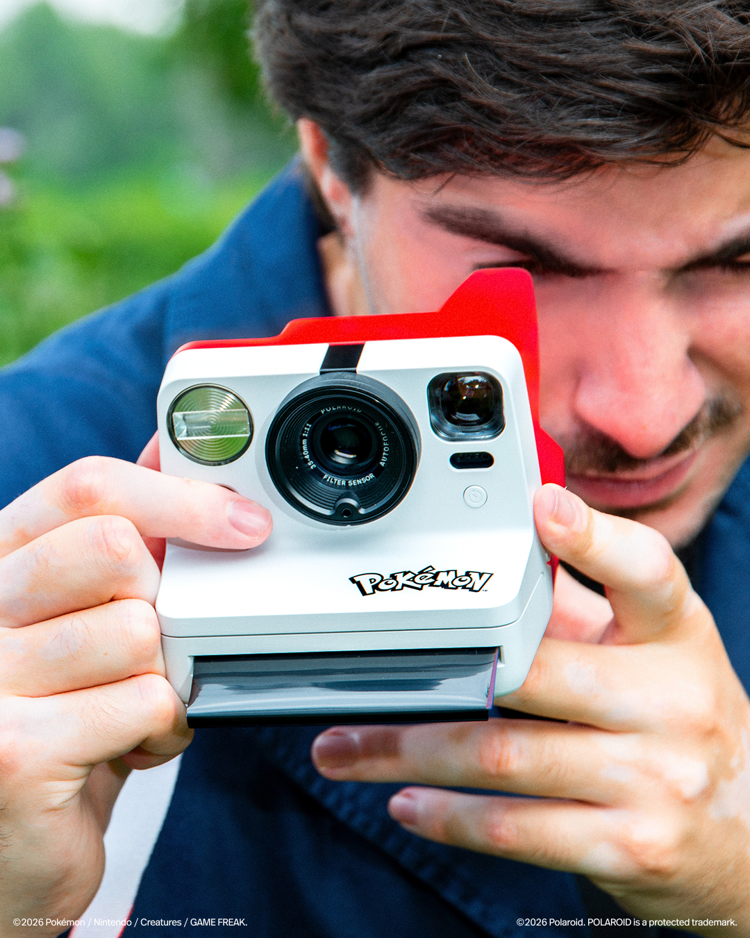 A pokeball themed polaroid camera. Its red and white and has the Pokemon logo on it.