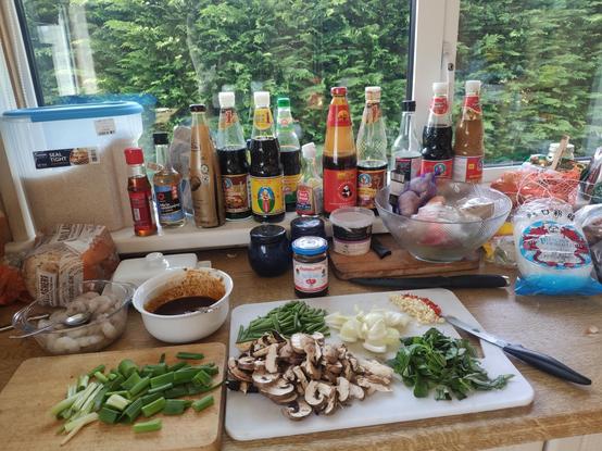 A surface with fresh ingredients ready to cook  and multiple sauce bottles maybe twenty in the background