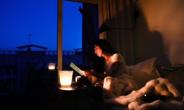 Una mujer lee en su casa con ayuda de una vela  en la localidad de El Masnou (Barcelona) durante el corte de suministro eléctrico. (EFE / Enric Fontcuberta)
