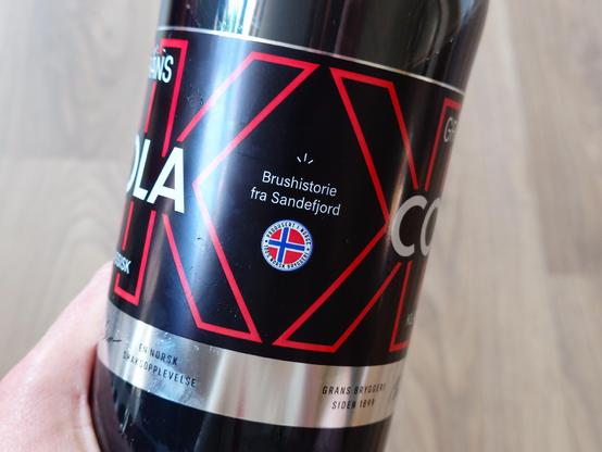"Brushistorie fra Sandefjord" together with a Norwegian flag on the side of the bottle.