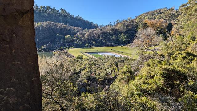 In the distance, nestled among the bushes, is a flat of grassland with a pool in the middle.
