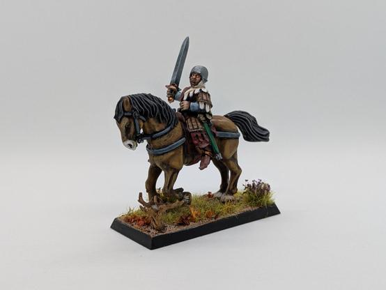 Un escudero montado sobre un caballo marrón, con una espada en la mano. Viste una túnica blanca y roja y sobre ella una armadura de cuero clara.
