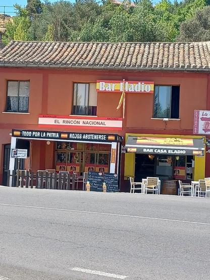 Fachada de un bar en Ávila llamado «Casa Eladio». Tiene varios carteles con los colores de la bandera de España y mensajes como «Zona Nacional» y «Rojos abstenerse».