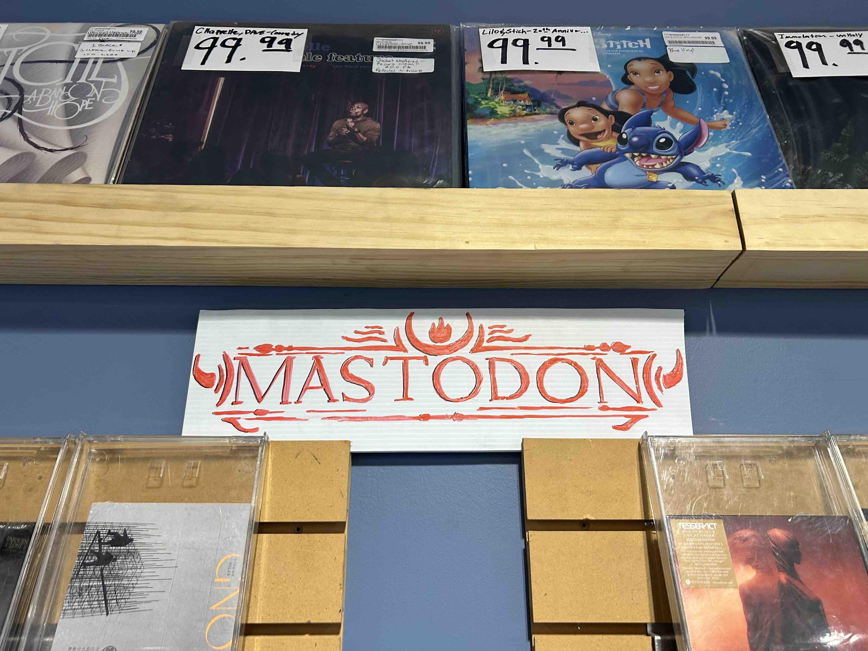 music store wall displaying recirds and the logo for a band named mastodon