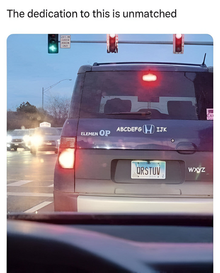 Back of a Honda Element.

Honda H logo is surrounded by ABCDEFG and IJK
T is taken off Element and replaced with OP to read ELEMEN OP
License plate is QRSTUV and the decal beside it reads WXYZ.