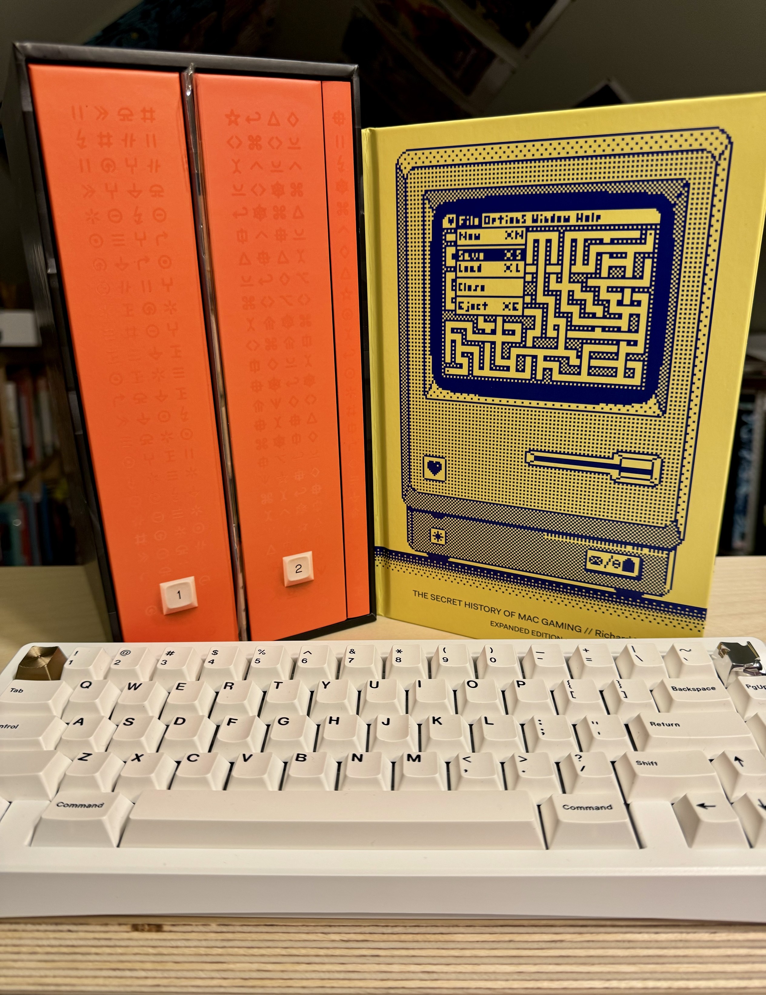 A photo of Shift Happens by Marcin Wichary, The Secret History of Macintosh Gaming by Richard Moss, and a Bauer Lite First Edition with GMK Minimal.