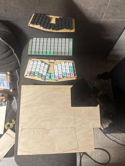 Three very small keyboards and a somewhat cut up piece of wood. From top to bottom the keyboards are a 44-key Atreus, a Prionic, and a 42-key Atreus.