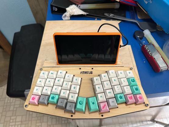 The mostly-assembled crashdeck. Behind the keyboard is a raspberry pi in an orange case with a display mounted on the front, nestled in a wooden bracket hot glued in place to hold it.