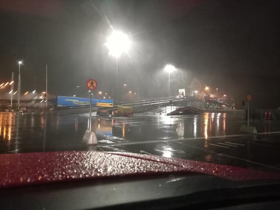 Auffahrt-Rampe zum Schiff. Es regnet, đer Asphalt ist nass, das Licht der Hafenbeleuchtung spiegelt sich darin.