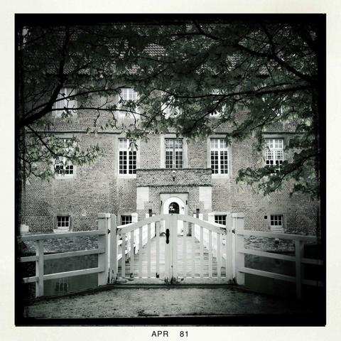 A b/w Hipstamatic shot of a gate and bridge with Burg Hülshoff, home of German author Annette von Droste-Hülshoff, in the background.