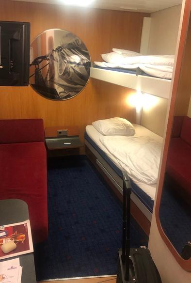 My hut. On the left a red couch, and on the right a bunk bed. In the middle a mirror-like think that I think is supposed to mimic a porthole. There's also a television on the wall on the left side.