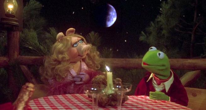The starry-eyed and voluptuous Miss Piggy in her cascades of blonde curls and knock-out pink evening gown shares a glass of sparkling wine with her handsome beau, Kermit the Frog. Above them in the dark sky is a large crescent Moon, lit from the right. Scene is from The Muppet Movie (1979). 

https://Wikipedia.org/wiki/The_Muppet_Movie