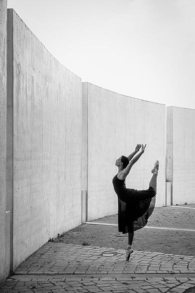 Balletttänzerin in urbaner Umgebung vor Betonmauern auf Spitze stehend