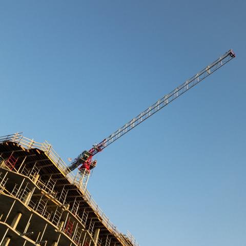 Looking up at a crane over a building under construction