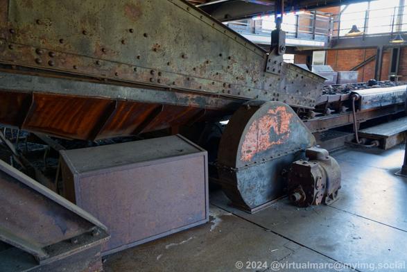 Side view of a conveyor belt transporting the coal inside the mine hall.