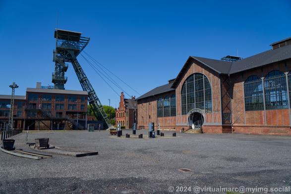 A photo of the area in front of the machine hall and the mine hall with the right winding tower.