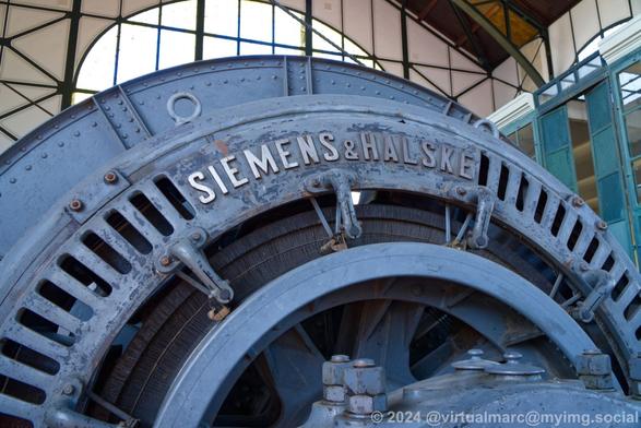 A detail photo of a big blue generator. The name of the Manufacturer "Siemens & Halske" is written on the top.