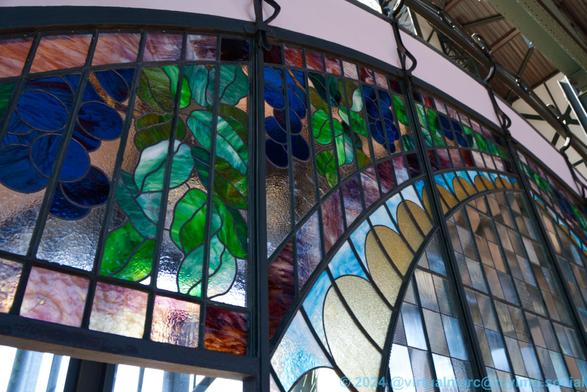 A detail phozo of the colorful glass window of the art nouveau entrance portal. The outer ring contains leaves and blue berries.