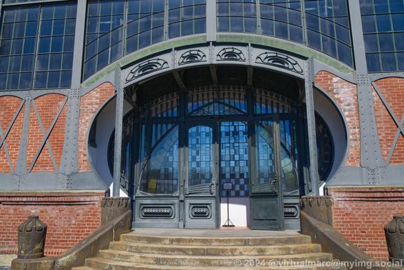 A photo of the art nouveau entrance portal from the outside, with stairs going up to the doors.