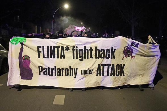 Fronttransparent mit dem Text: "Flinta* fight back - Patriarchy under attack" dahinter viele Menschen.
