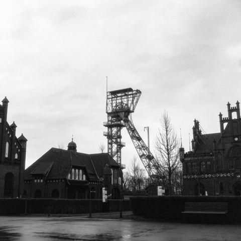 Black and white photo of the headframe of shaft IV, the horse stables and part of the administrative building at Zollern colliery in Dortmund.