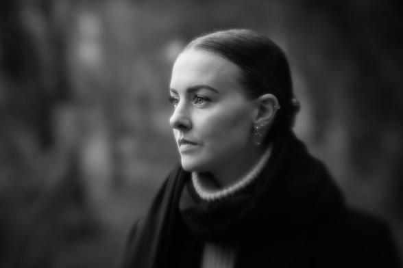 Weichzeichener-Portrait einer jungen Frau, die zur Seite aus dem Bild herausschaut.