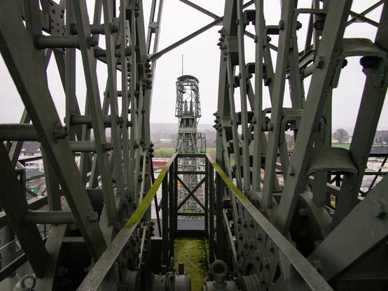 Color photo of the head frame of shaft IV at Zollern colliery in Dortmund as seen through the bullweels of shaft II.