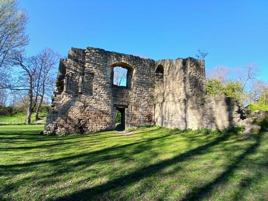 Ruins in a field. There is a right angle corner with doorways and arch ways in