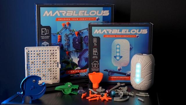Marblelous Murmelbahn Starter Set mit zusätzlichem Dropper-Element steht repräsentativ auf einem Tisch, der vor einem schwarzen Hintergrund steht und von links leicht bläulich angestrahlt wird. Foto (c) Marblelous.tech.
