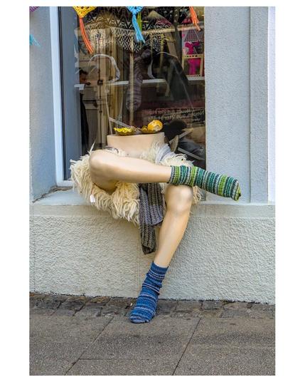 The image titled "Fensterfreitag" by Heiko Schulz, shared on Pixelfed, features a window scene with a small, colorful toy figure placed on the windowsill. The figure appears to be gazing outward, evoking a sense of contemplation or longing. The window is partially open, allowing natural light to illuminate the scene and create soft shadows. The background reveals a blurred view of the outdoors, suggesting a tranquil environment. The composition emphasizes the contrast between the vivid colors of the toy and the muted tones of the surroundings, highlighting the figure as the focal point.