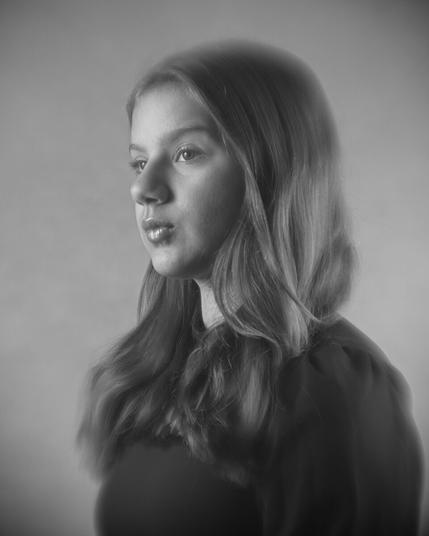 Softfokus Studio-Portrait eines 12jährigen Mädchens, das nach links aus dem Bild hinausschaut.