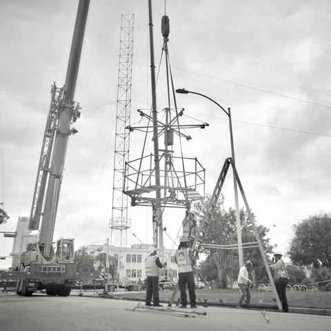 A black and white film photo. Workers are disassembling the Moonlight Tower at W. 12 Street and Rio Grande Street, for what I was told by one of the crew, a refurbishment. Sunday, April 27, 2025.