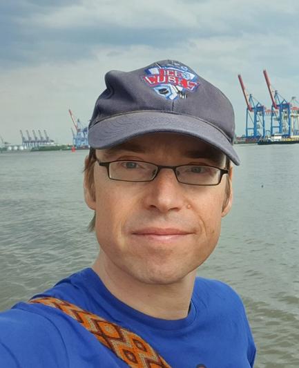 Ich im Portrait mit blauem Käppi an der Elbe, im Hintergrund Hafenkräne