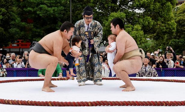 Amateur sumo wrestlers hold babies during Nakizumo.