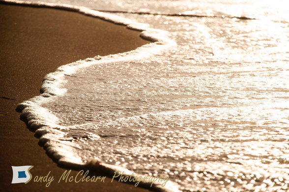 Line of sea foam at the leading edge of a wave at the beach.