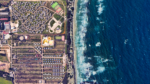 a satellite picture of a seaside resort complex and the sea. th picturee is split in two with the blue sea on the right and the resort + camping on the left