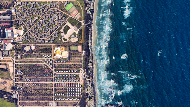 a satellite picture of a seaside resort complex and the sea. th picturee is split in two with the blue sea on the right and the resort + camping on the left