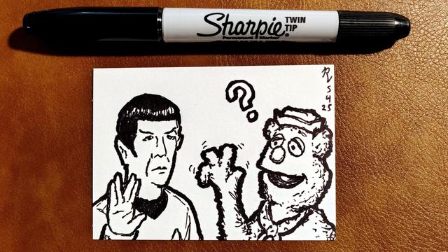 Marker drawing on an artist trading card of Spock from Star Trek meeting Fozzie Bear. Spock is giving Fozzie the split-finger Vulcan salute, and Fozzie is confusedly trying to reciprocate despite having one fewer finger on his hand. The drawing is signed with my "RV" signature glyph and dated 5-3-25. The double-tipped black Sharpie marker used to draw the image rests on the table above the card.