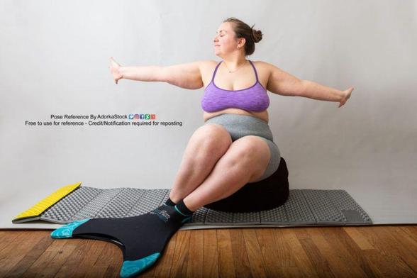 A fat white woman wearing a mermaid fin on her feet sitting on a black pouf, arms outstretched to either side of her, face in profile.