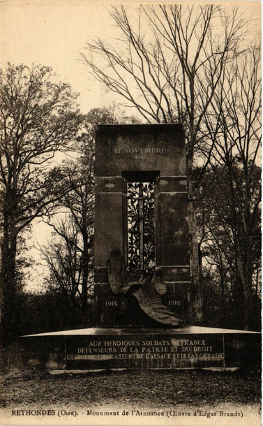 an old  photograph of the orginial monument before it was destroyed, it is a sepia-toned photo, it is a large rectangular arch with a big sword coming down in the center,  impaling an eagle, on its back, its wings outstretched. it is to commemorate the returning of the region to the french folllowing world war one