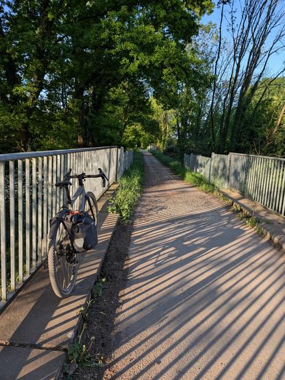 Ein Fahrrad lehrn an einer Absperrung, die Sonne scheint von hinten und wirft lange Schatten