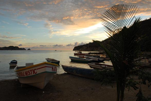 A quiet bay at the sea at sundown with various wooden boats on the beach and in the water