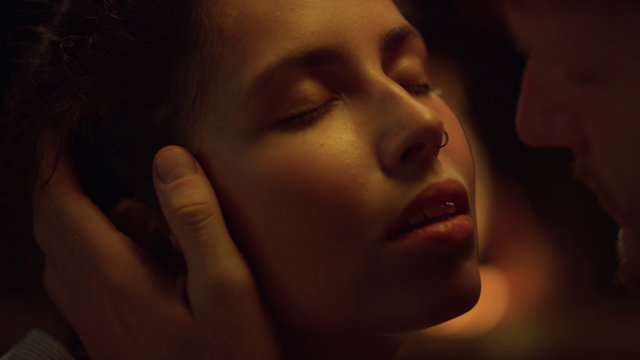 Woman's face being held by a man's as she closes her eyes in expectation.