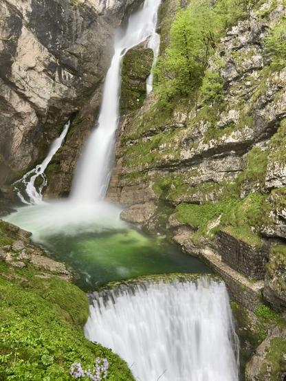 One big & one small cascade, with dam in foreground.

Water flows from the cave passage through a fault line in the Komarca rock wall, and its outflow is a karst spring at an altitude of 836m. After a few rapids, the water starts flowing diagonally and then falls into the depths almost vertically. The total height difference of the higher, right-hand cascade is 78m.