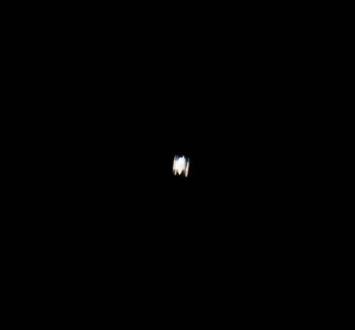 A small, blurry, white light is visible in the center of a black background.